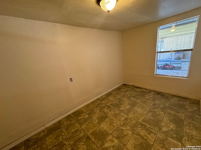 unfurnished room with a textured ceiling