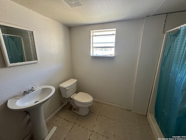 bathroom featuring a shower with curtain, a textured ceiling, and toilet