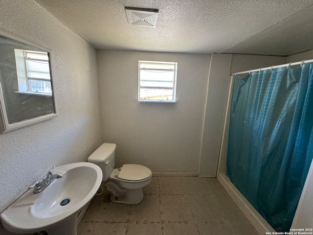 bathroom with toilet, sink, a textured ceiling, and a shower with shower curtain