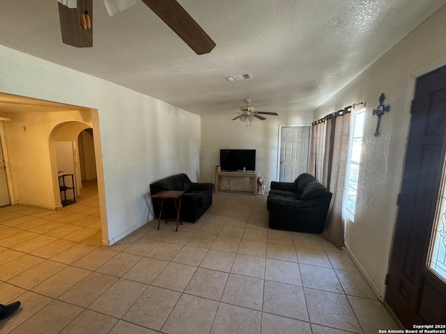 living room with light tile patterned flooring, ceiling fan, and a textured ceiling