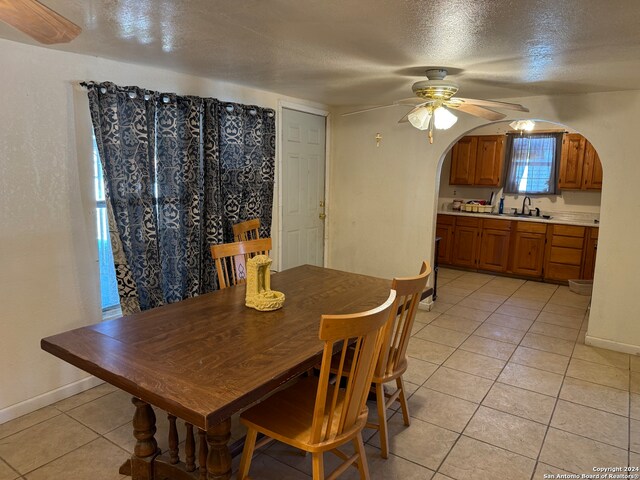 dining space with light tile patterned flooring, ceiling fan, a textured ceiling, and sink