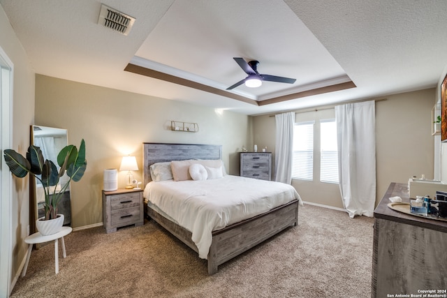 bedroom with ceiling fan, ornamental molding, a tray ceiling, and carpet