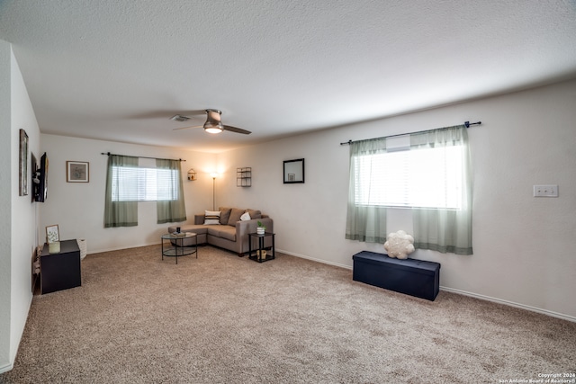 living room with ceiling fan, a textured ceiling, and light carpet