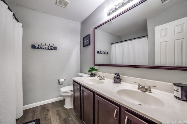 bathroom with toilet, vanity, wood-type flooring, and a textured ceiling