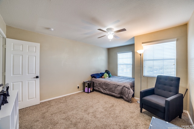 carpeted bedroom featuring ceiling fan and a textured ceiling