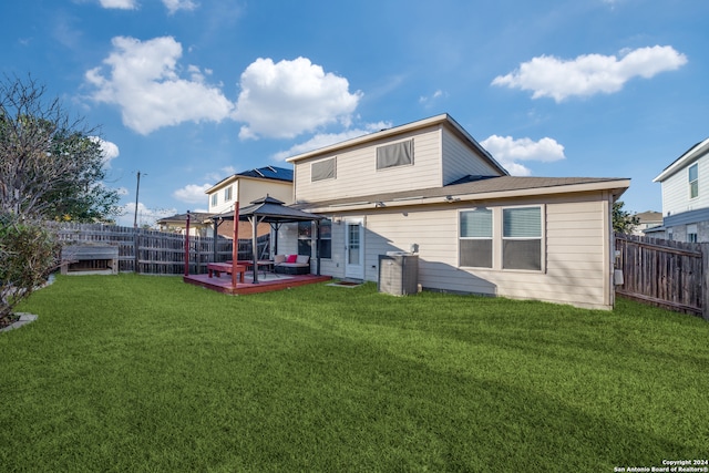 rear view of property featuring a lawn, a wooden deck, and a gazebo