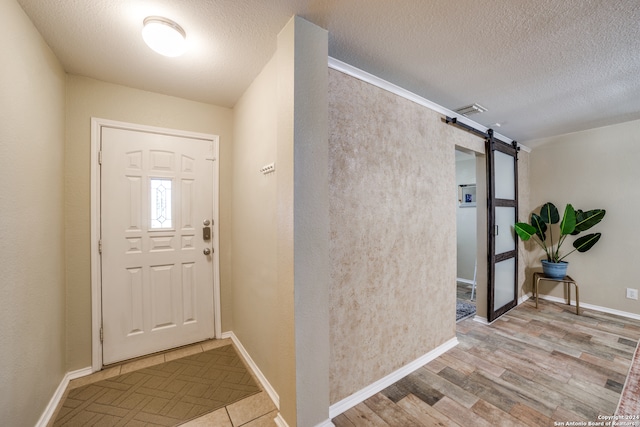 foyer featuring a textured ceiling, a barn door, and light hardwood / wood-style flooring