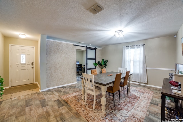 dining area with a textured ceiling, hardwood / wood-style floors, and a barn door