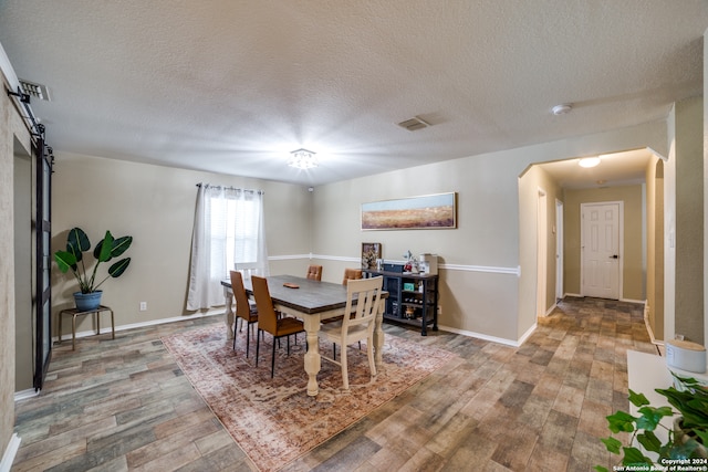 dining space featuring wood-type flooring and a textured ceiling