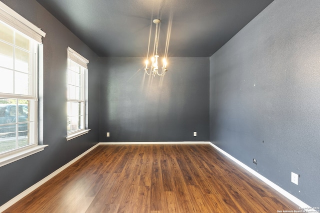 spare room with hardwood / wood-style flooring and a chandelier