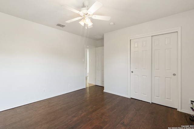 unfurnished bedroom with ceiling fan, a closet, and dark wood-type flooring