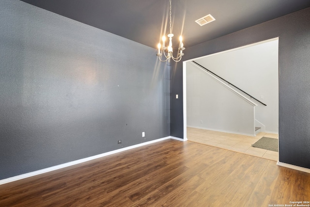 empty room with hardwood / wood-style floors and a notable chandelier