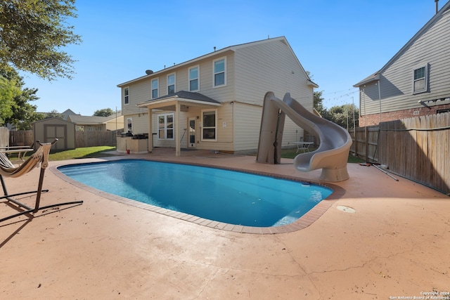 back of house with a patio, a fenced in pool, and a storage unit