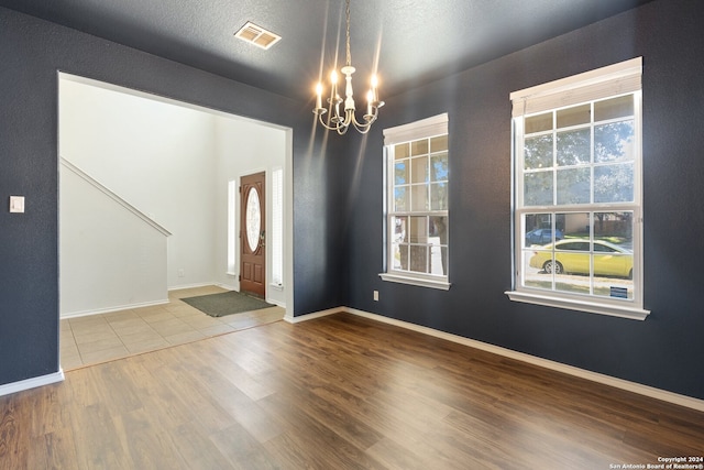 entrance foyer with wood-type flooring, a textured ceiling, and an inviting chandelier