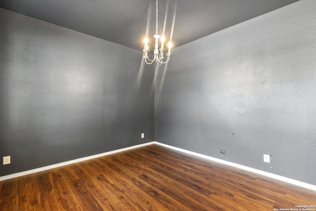 empty room featuring a chandelier and hardwood / wood-style floors