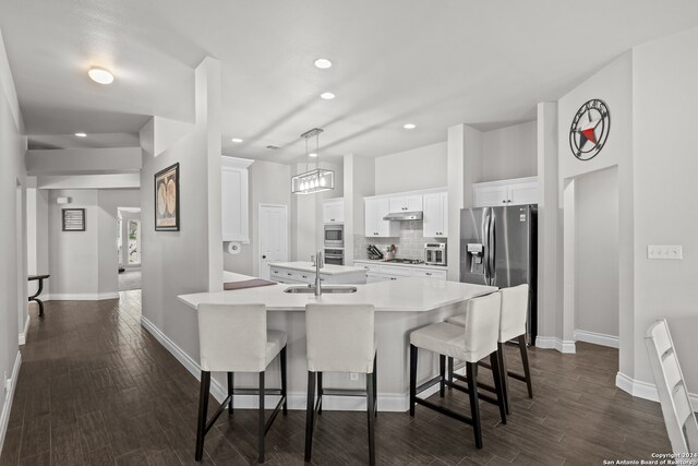 kitchen featuring stainless steel appliances, a breakfast bar area, white cabinetry, and dark hardwood / wood-style floors