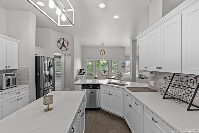 kitchen featuring white cabinetry, appliances with stainless steel finishes, light stone countertops, decorative backsplash, and sink