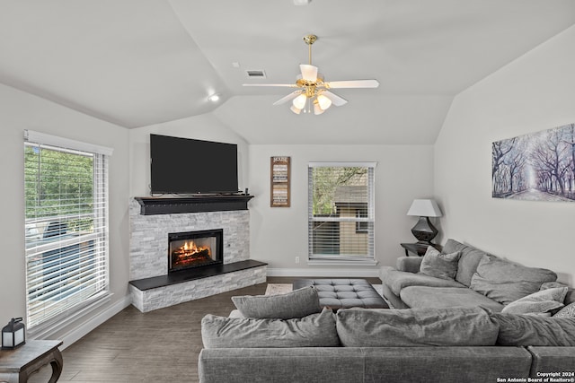 living room featuring dark hardwood / wood-style flooring, a wealth of natural light, lofted ceiling, and a stone fireplace