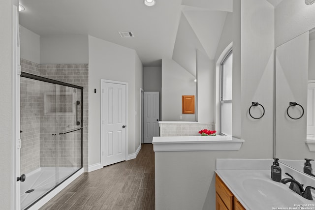 bathroom with hardwood / wood-style floors, a shower with shower door, vanity, and lofted ceiling