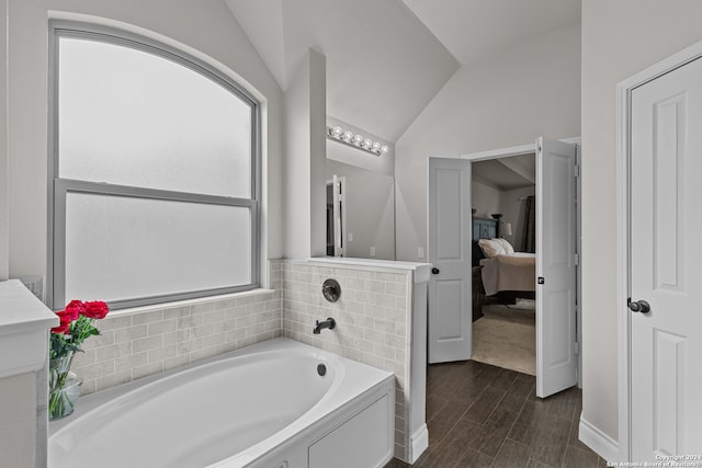 bathroom with wood-type flooring, a bathtub, and vaulted ceiling