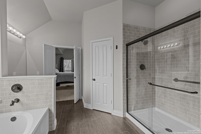 bathroom featuring wood-type flooring, shower with separate bathtub, and vaulted ceiling