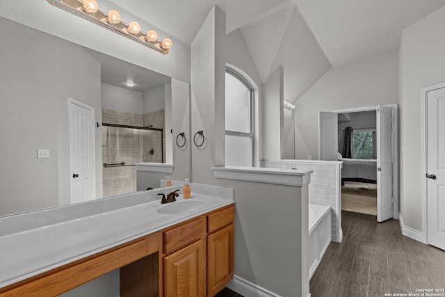 bathroom featuring hardwood / wood-style floors, vanity, separate shower and tub, and vaulted ceiling