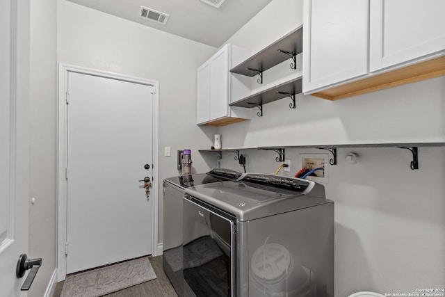 laundry area with washer and clothes dryer, cabinets, and light hardwood / wood-style flooring