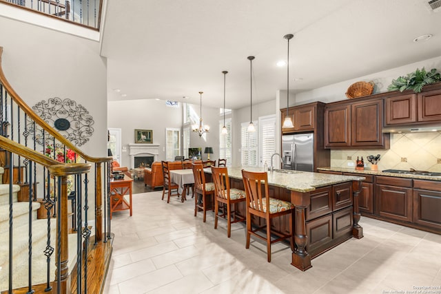 kitchen with light stone countertops, appliances with stainless steel finishes, an island with sink, and light tile patterned flooring