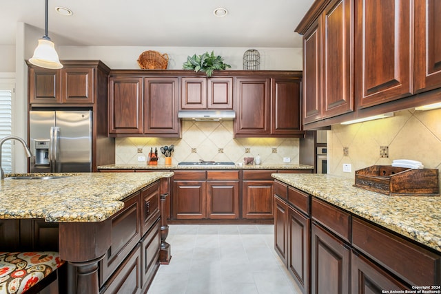 kitchen featuring tasteful backsplash, light stone countertops, decorative light fixtures, and stainless steel appliances