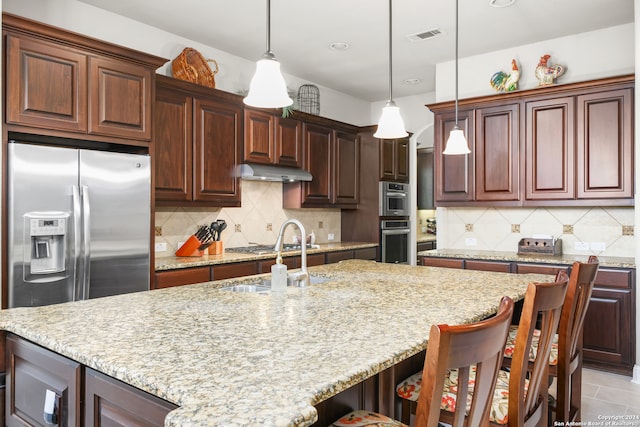 kitchen with decorative backsplash, sink, a breakfast bar, and decorative light fixtures