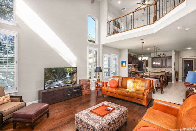 living room featuring a towering ceiling, ceiling fan with notable chandelier, and dark hardwood / wood-style floors