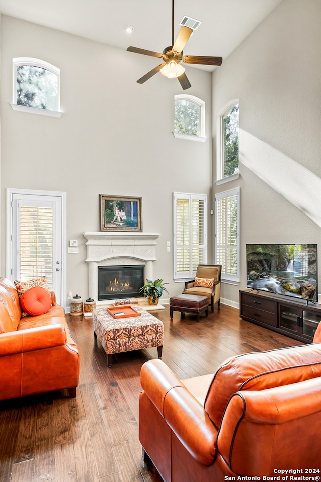 living room featuring a high ceiling, hardwood / wood-style flooring, and ceiling fan