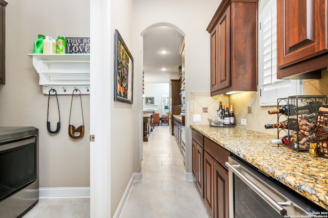 kitchen featuring backsplash, light tile patterned floors, light stone countertops, and washer / dryer