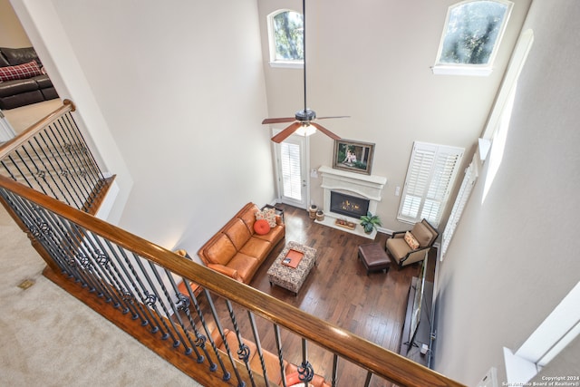 living room with a towering ceiling, wood-type flooring, ceiling fan, and plenty of natural light