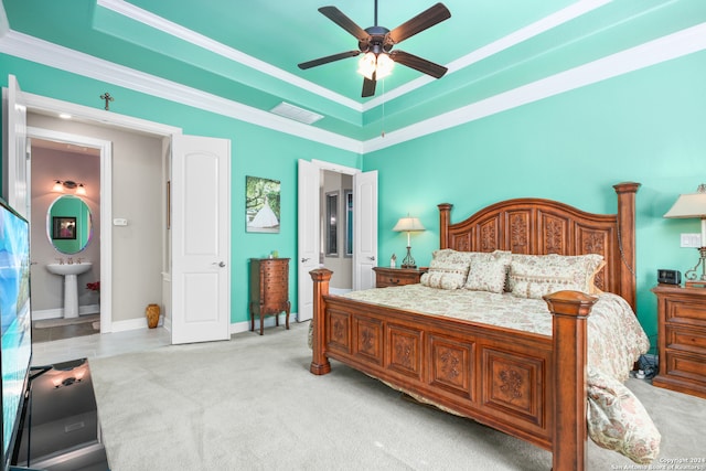 carpeted bedroom featuring ceiling fan, ensuite bath, a tray ceiling, and ornamental molding