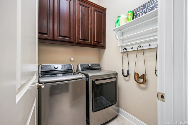 laundry area featuring light tile patterned floors, cabinets, and washing machine and clothes dryer