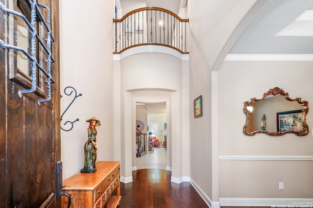 entryway with dark wood-type flooring and crown molding