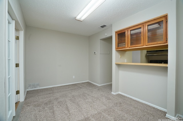 carpeted empty room featuring a textured ceiling