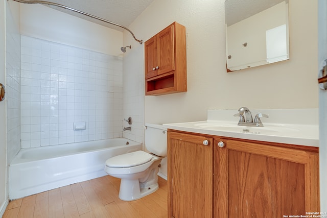 full bathroom with wood-type flooring, vanity, a textured ceiling, toilet, and tiled shower / bath