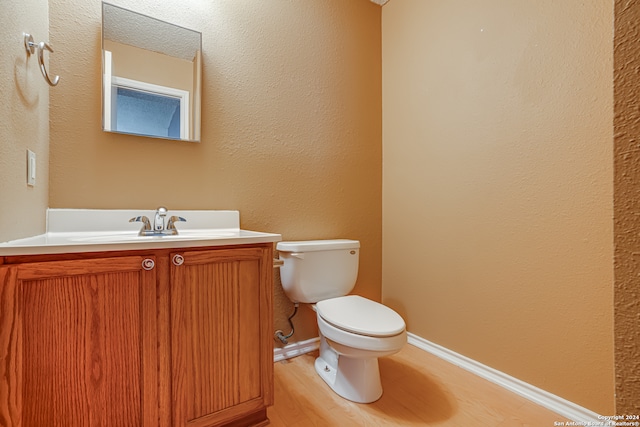 bathroom with hardwood / wood-style floors, vanity, and toilet