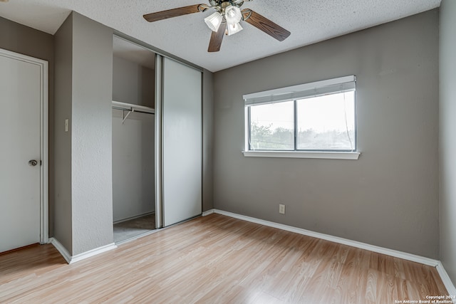 unfurnished bedroom featuring light hardwood / wood-style floors, ceiling fan, a textured ceiling, and a closet