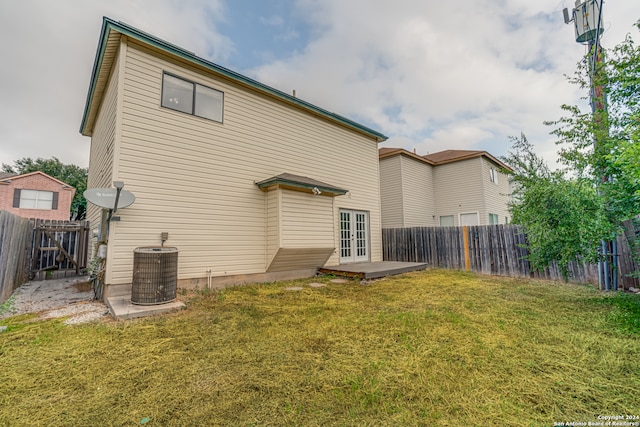 back of property with central AC, a yard, and french doors