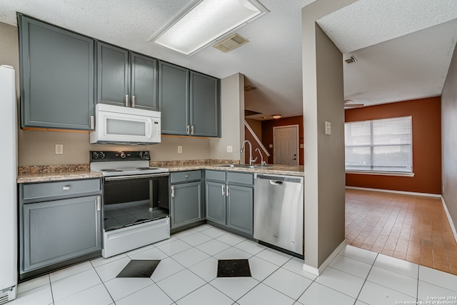 kitchen with white appliances, a textured ceiling, light hardwood / wood-style flooring, and gray cabinets