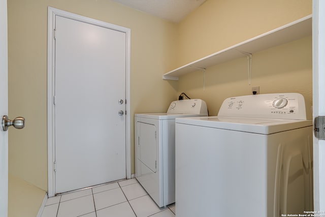 washroom with washer and clothes dryer, a textured ceiling, and light tile patterned floors