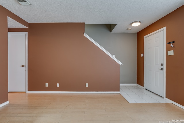 entryway with a textured ceiling and light wood-type flooring