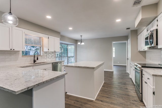 kitchen featuring a center island, white cabinets, decorative light fixtures, and appliances with stainless steel finishes