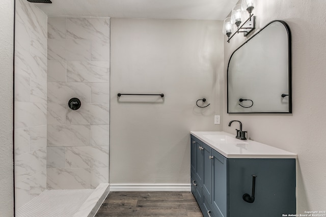 bathroom featuring wood-type flooring, vanity, and a tile shower