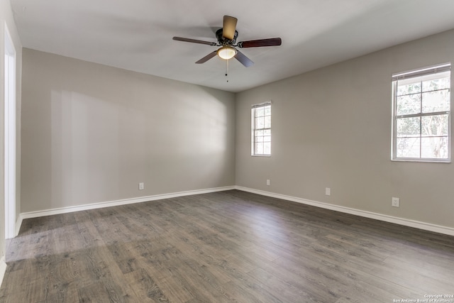 empty room with dark hardwood / wood-style floors, a wealth of natural light, and ceiling fan