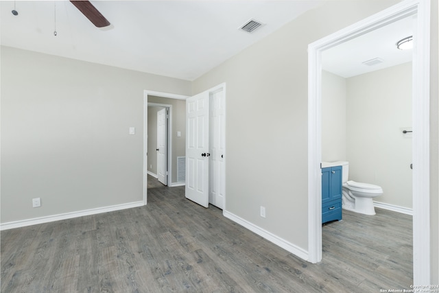 unfurnished bedroom with ensuite bathroom, ceiling fan, and dark hardwood / wood-style floors