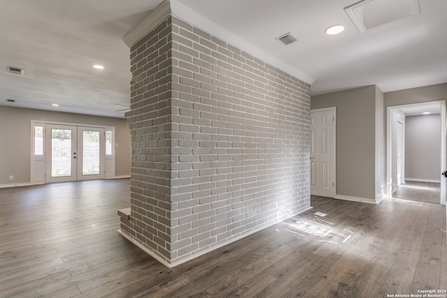 empty room with dark hardwood / wood-style floors, brick wall, and french doors